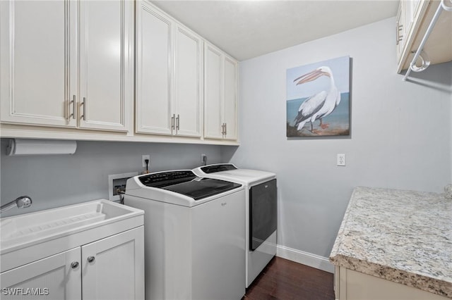 clothes washing area featuring cabinets, washer and dryer, dark hardwood / wood-style floors, and sink