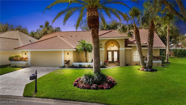 mediterranean / spanish home featuring a front lawn, a garage, and french doors