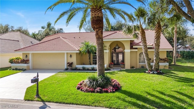 mediterranean / spanish home featuring a front yard, a garage, and french doors