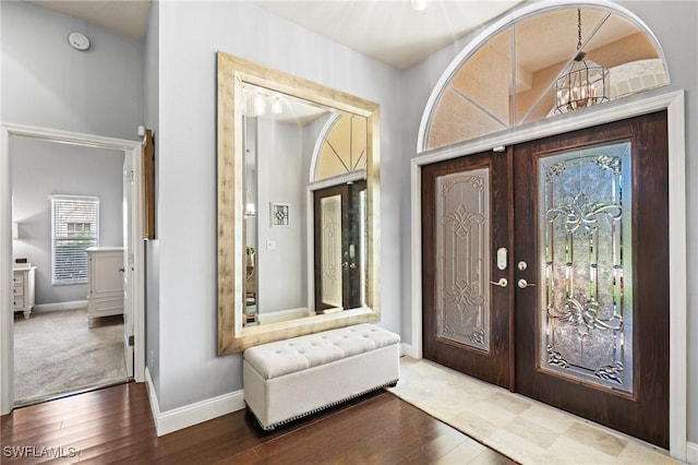 foyer entrance featuring an inviting chandelier, dark hardwood / wood-style flooring, and french doors