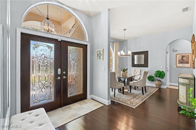 foyer with dark hardwood / wood-style floors, french doors, and a notable chandelier