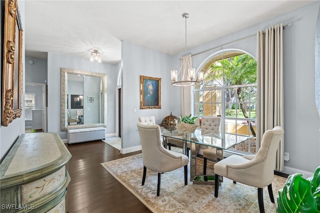 dining room with dark wood-type flooring and an inviting chandelier