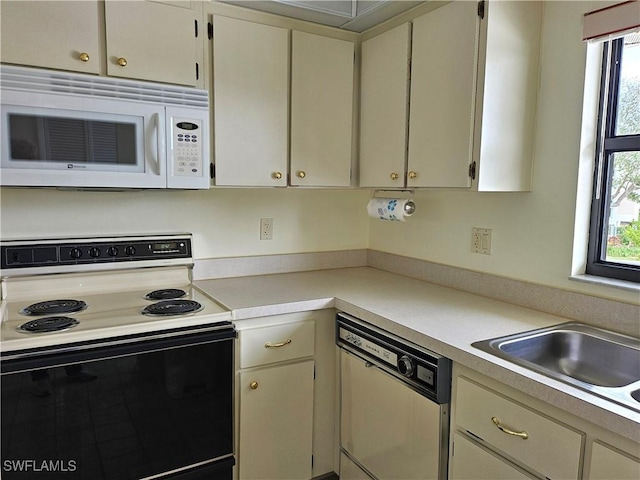 kitchen featuring dishwasher, sink, electric range oven, and cream cabinets