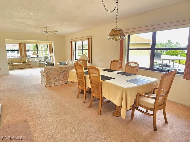 dining room featuring ceiling fan with notable chandelier and light colored carpet