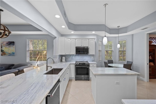 kitchen featuring decorative light fixtures, tasteful backsplash, sink, stainless steel appliances, and white cabinets