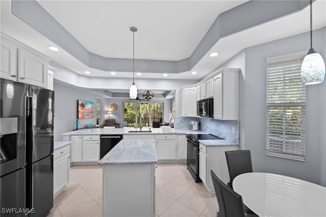 kitchen featuring decorative light fixtures, a kitchen island, black appliances, kitchen peninsula, and white cabinets