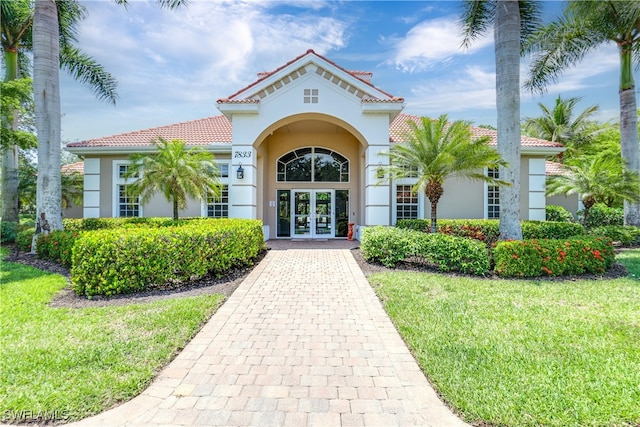 doorway to property with a lawn and french doors