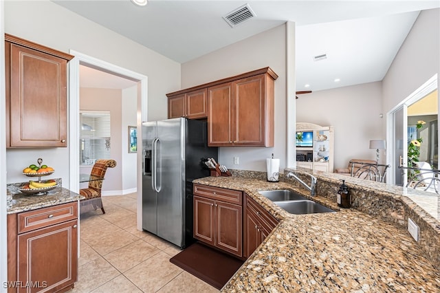 kitchen featuring a wealth of natural light, sink, stainless steel fridge, light tile patterned floors, and stone counters