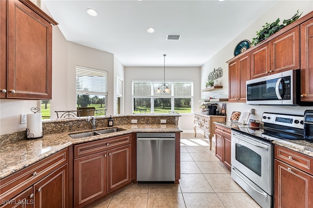 kitchen with light stone countertops, stainless steel appliances, a chandelier, and sink