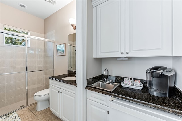 bathroom with a shower with shower door, toilet, vanity, and tile patterned flooring