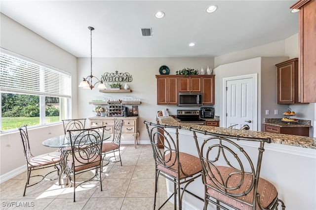 kitchen featuring decorative light fixtures, light stone countertops, stainless steel appliances, light tile patterned floors, and a chandelier