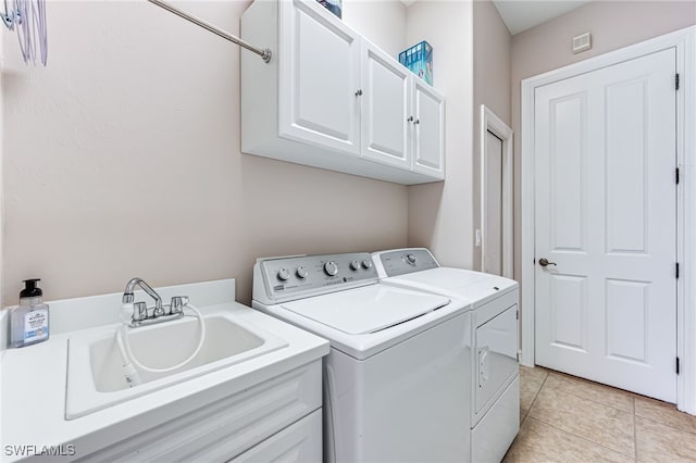 clothes washing area with cabinets, light tile patterned flooring, washing machine and clothes dryer, and sink