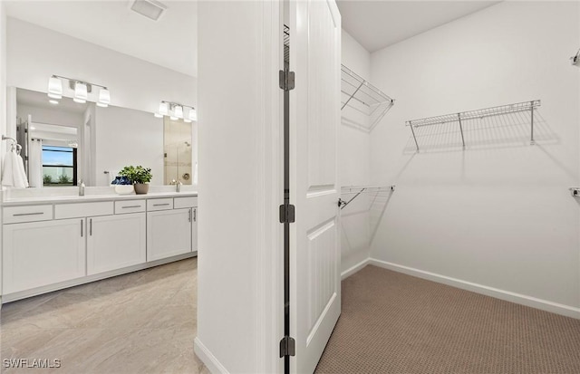 walk in closet with sink and light colored carpet