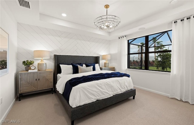 carpeted bedroom with an inviting chandelier and a tray ceiling