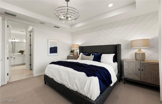 bedroom with ensuite bathroom, light carpet, a notable chandelier, and a tray ceiling