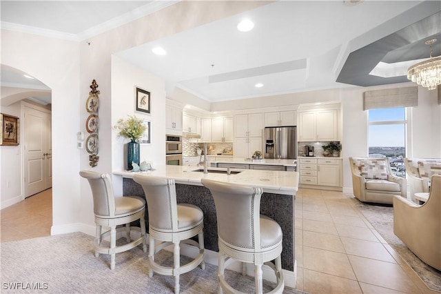 kitchen featuring a kitchen breakfast bar, appliances with stainless steel finishes, white cabinets, and backsplash