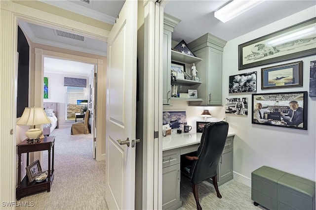 office space with light colored carpet, crown molding, and built in desk