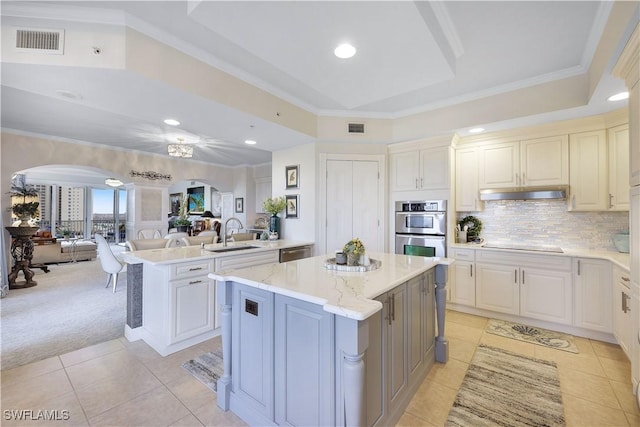 kitchen featuring light stone countertops, light colored carpet, stainless steel appliances, and a kitchen island