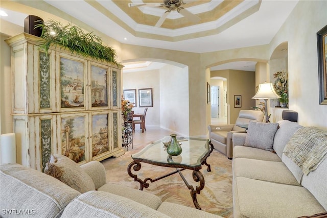 living room with ceiling fan, a raised ceiling, and ornamental molding