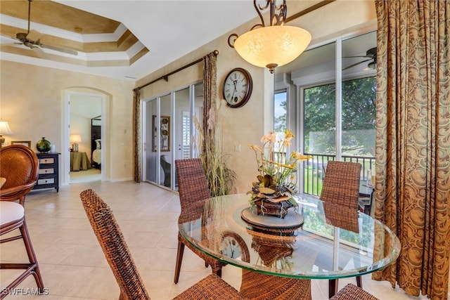 dining room with a healthy amount of sunlight, light tile patterned flooring, a tray ceiling, and ornamental molding