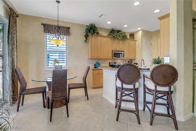 kitchen featuring decorative light fixtures, sink, light brown cabinets, and appliances with stainless steel finishes