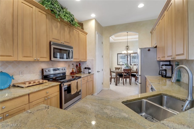 kitchen with tasteful backsplash, sink, hanging light fixtures, appliances with stainless steel finishes, and light brown cabinetry