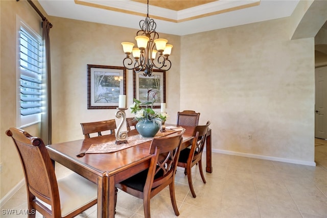 tiled dining space with ornamental molding, a raised ceiling, and a notable chandelier