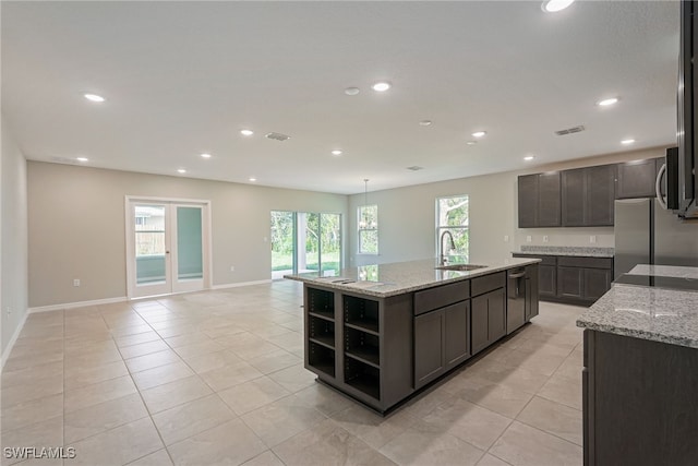 kitchen with sink, appliances with stainless steel finishes, an island with sink, and dark brown cabinets