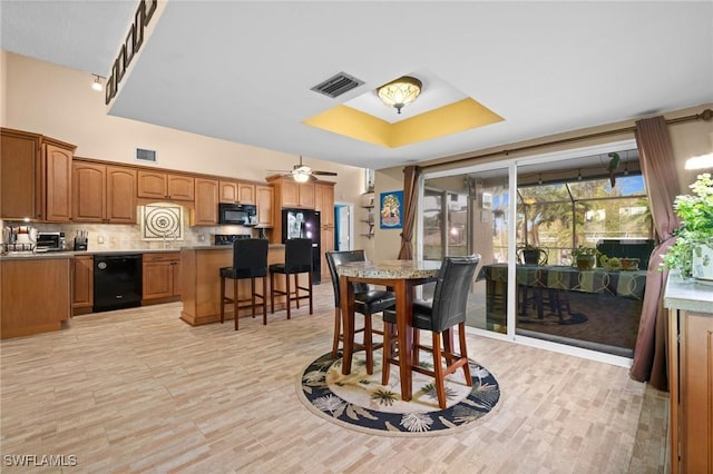 dining area featuring ceiling fan, sink, and a raised ceiling