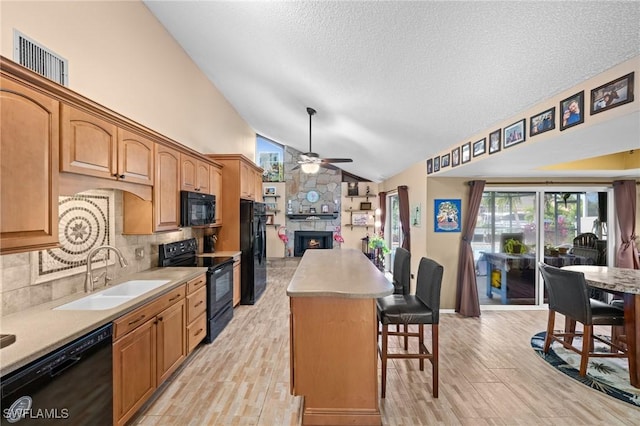 kitchen with backsplash, a kitchen island, black appliances, a kitchen bar, and sink