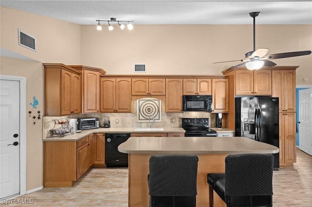 kitchen with black appliances, backsplash, sink, and a center island