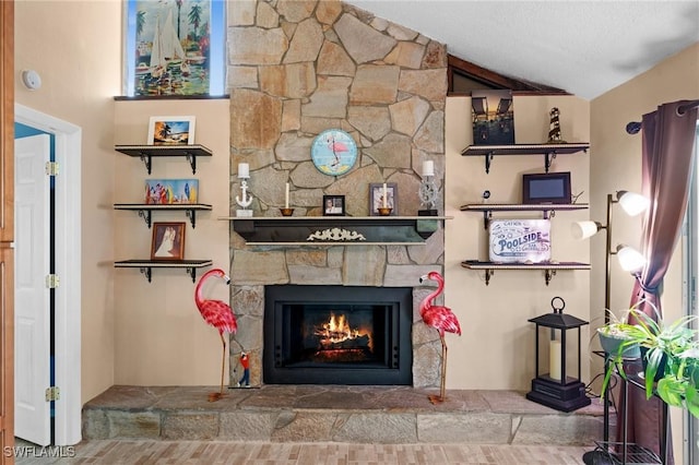 living room featuring vaulted ceiling, a textured ceiling, and a fireplace