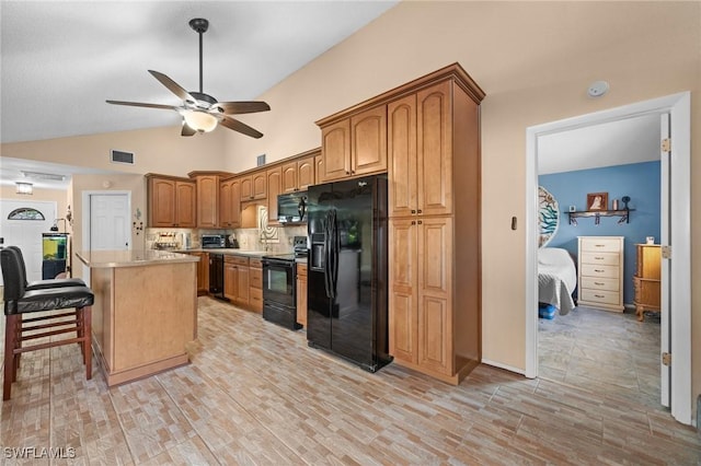 kitchen featuring ceiling fan, lofted ceiling, a center island, black appliances, and a breakfast bar