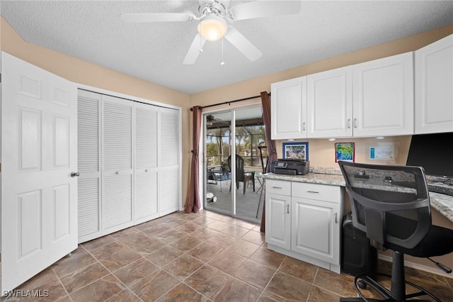 interior space with ceiling fan, a textured ceiling, and built in desk