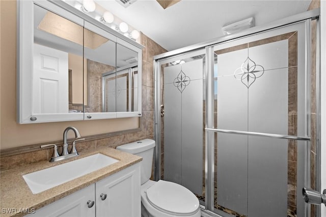 bathroom featuring a shower with shower door, toilet, and vanity