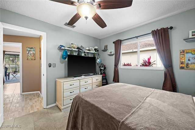 tiled bedroom featuring a textured ceiling and ceiling fan