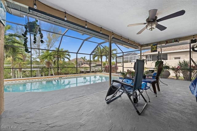 view of swimming pool featuring glass enclosure, a patio area, and ceiling fan