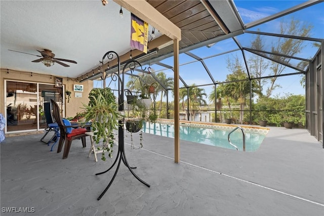 view of pool with ceiling fan, glass enclosure, and a patio area