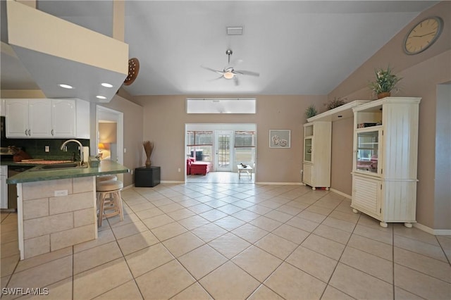 kitchen with white cabinets, tasteful backsplash, sink, kitchen peninsula, and a breakfast bar area