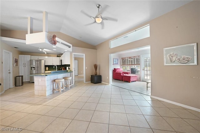 kitchen featuring light tile patterned floors, a kitchen breakfast bar, white cabinets, sink, and kitchen peninsula