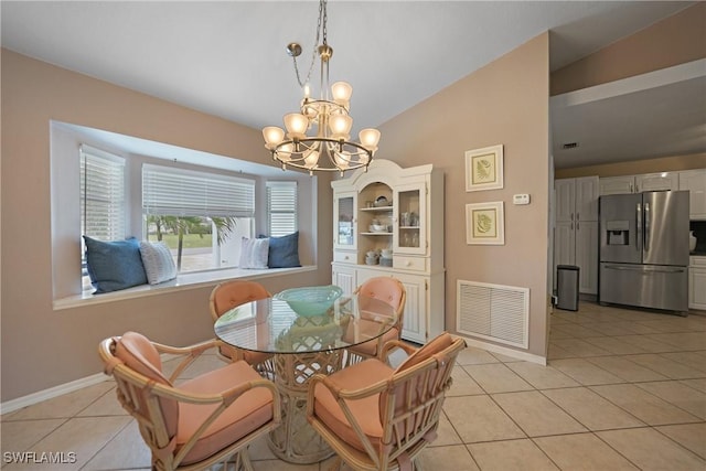 tiled dining space featuring a chandelier and vaulted ceiling