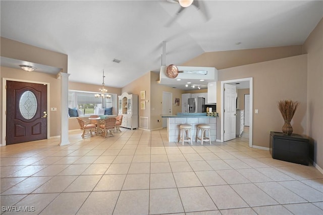 kitchen with lofted ceiling, white cabinetry, stainless steel fridge with ice dispenser, kitchen peninsula, and light tile patterned floors