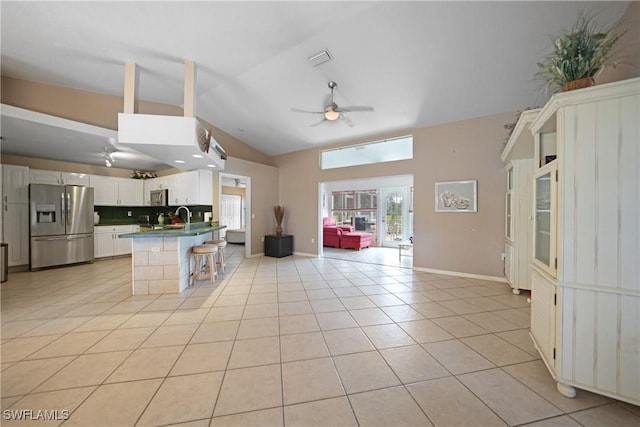 kitchen featuring stainless steel fridge with ice dispenser, white cabinetry, a kitchen breakfast bar, backsplash, and light tile patterned flooring