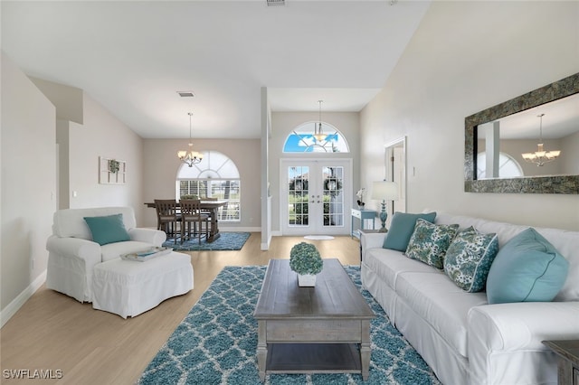 living room featuring a notable chandelier, wood-type flooring, high vaulted ceiling, and french doors