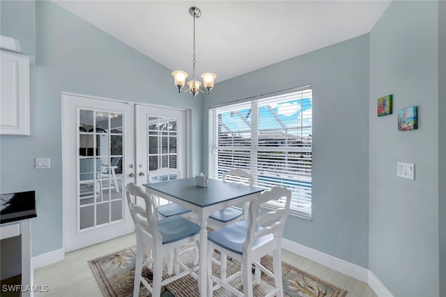 dining space with lofted ceiling, french doors, and an inviting chandelier