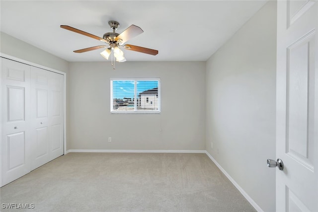 unfurnished bedroom featuring light carpet, ceiling fan, and a closet