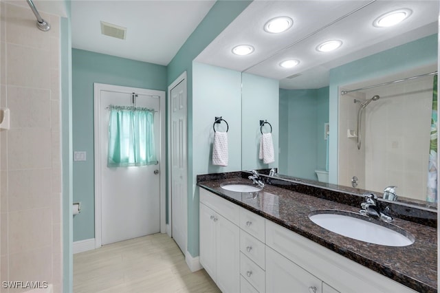 bathroom featuring vanity, tiled shower, and toilet