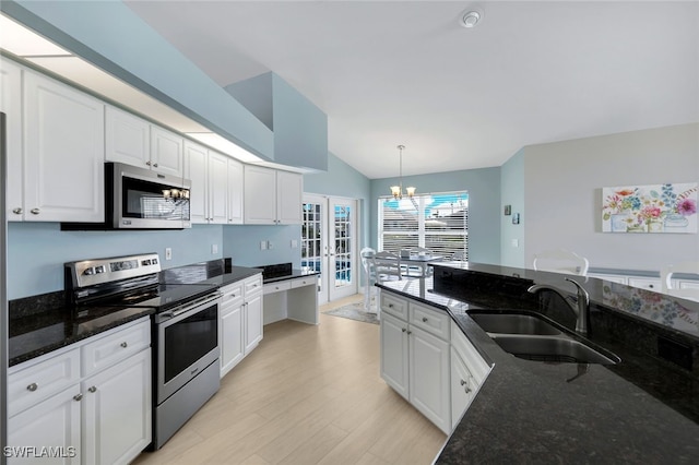 kitchen with sink, appliances with stainless steel finishes, white cabinets, decorative light fixtures, and dark stone counters