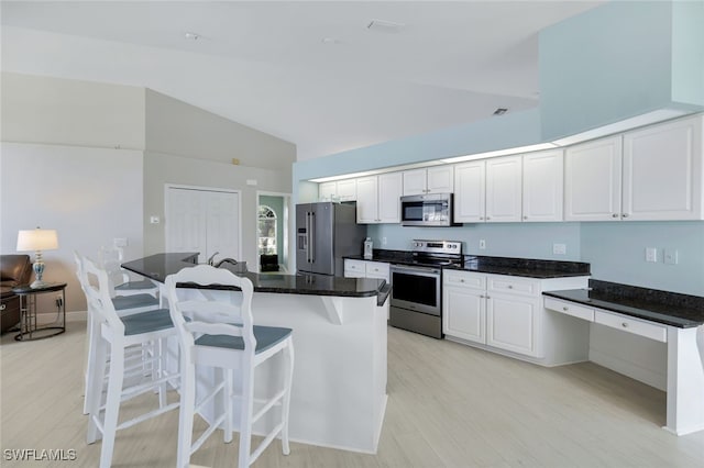 kitchen featuring white cabinetry, lofted ceiling, stainless steel appliances, and a kitchen island