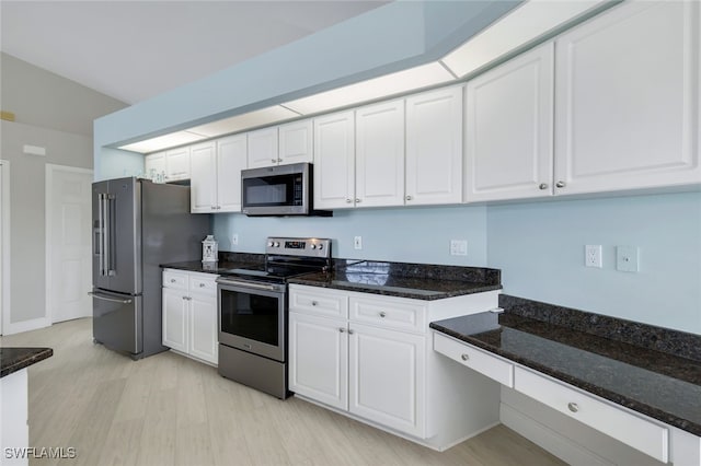 kitchen with white cabinetry, stainless steel appliances, light hardwood / wood-style floors, and dark stone countertops